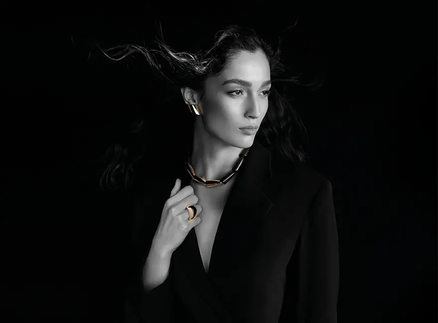 A woman posing, wearing Vhernier Calla necklace, Vague earclips and ring