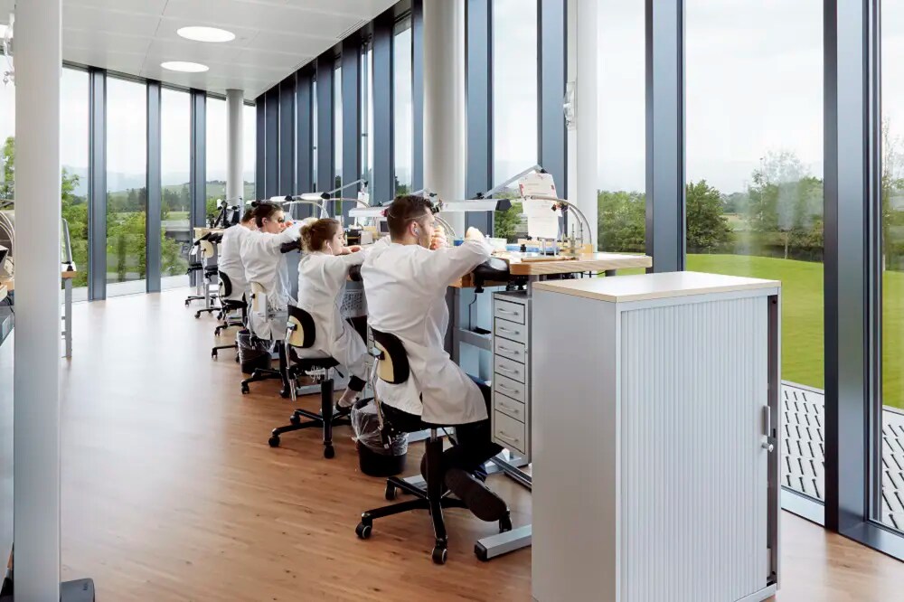 A workshop with several stands where people are working on watches