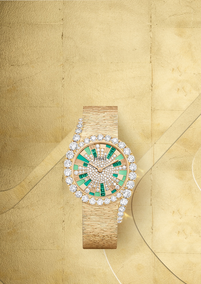 A golden watch encrusted with diamonds and green gemstones