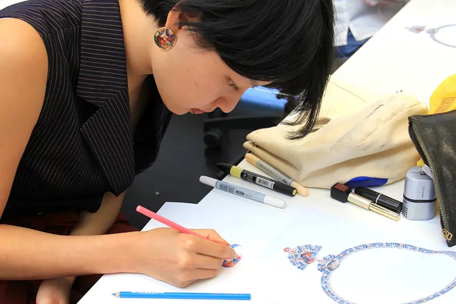 A woman working on a sketch of jewellery