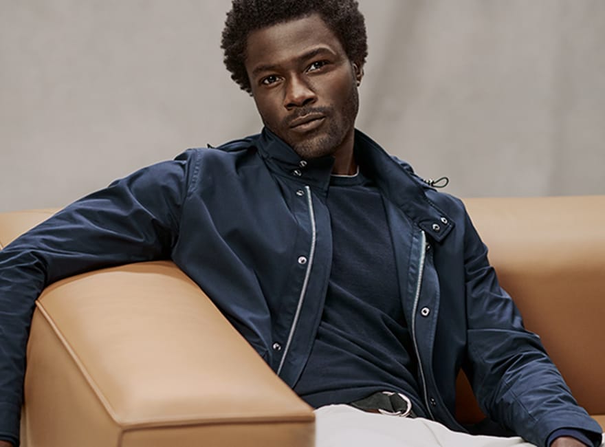 Model sitting wearing a navy blue jacket and t-shirt 