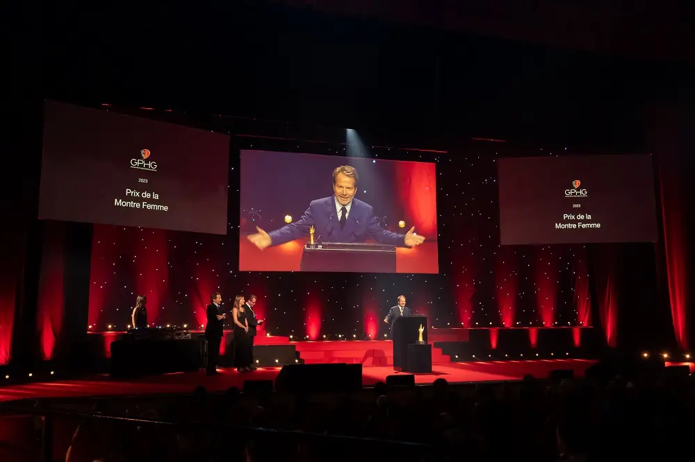 A man on stage, receiving a prize