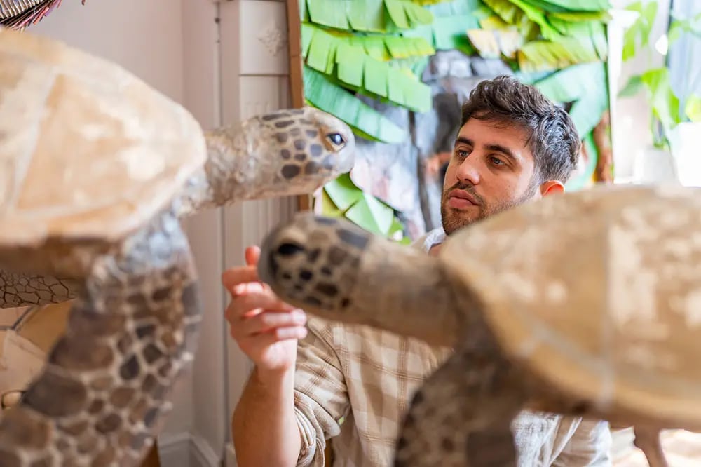 A man standing among sculptures of turtles