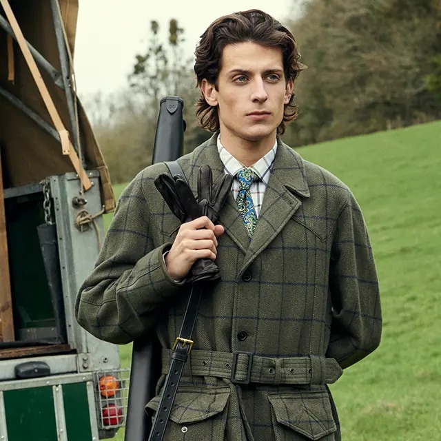 A man in the countryside wearing a dark green coat